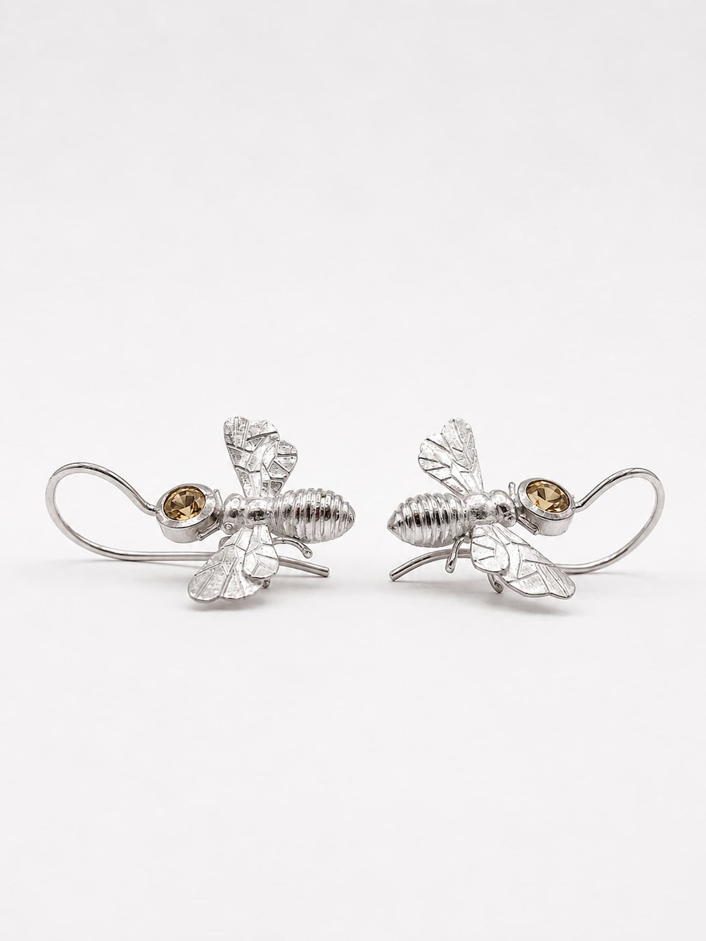 Ein Paar handgefertigter Bienen Ohrhänger aus 925 Silber, 
einander zugewandt – Detailansicht der strukturierten Oberfläche, 
Flügel und hellgelben Citrine – Einzelstück Atelier Q Köln.