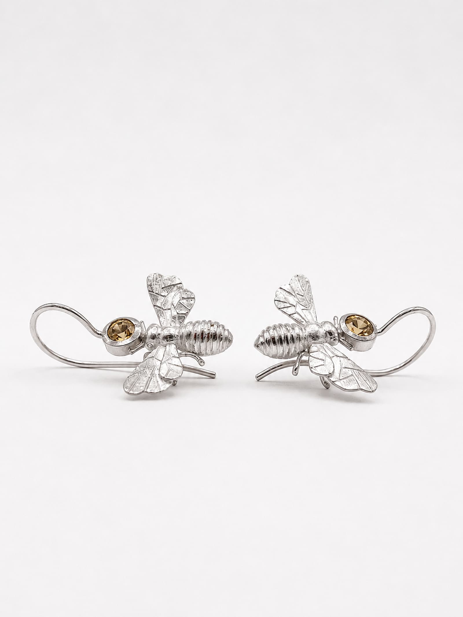 Ein Paar handgefertigter Bienen Ohrhänger aus 925 Silber, 
einander zugewandt – Detailansicht der strukturierten Oberfläche, 
Flügel und hellgelben Citrine – Einzelstück Atelier Q Köln.