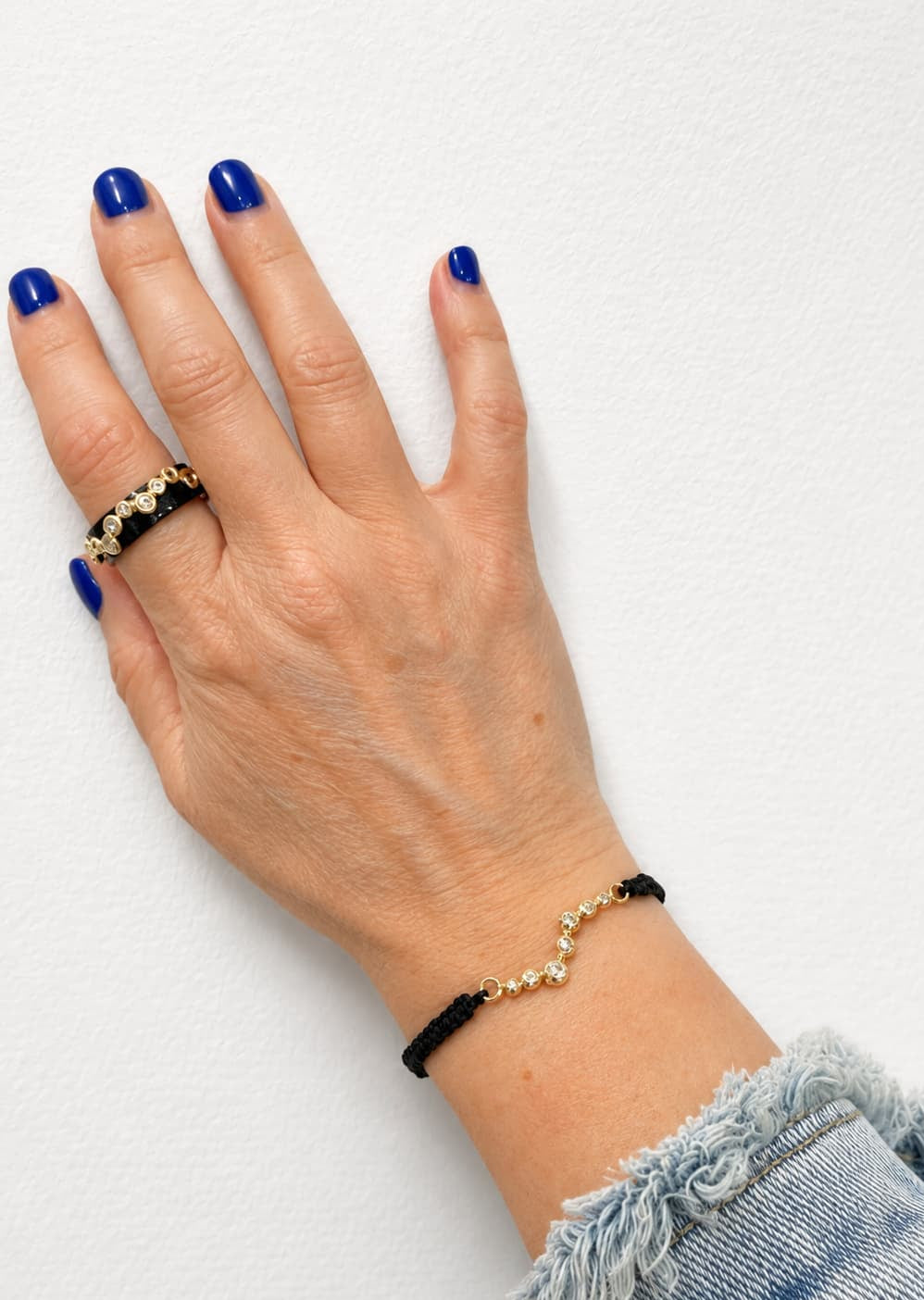 Feines Armband aus 750 Gelbgold mit brillantbesetzten Donut-Elementen und schwarzem Baumwollband