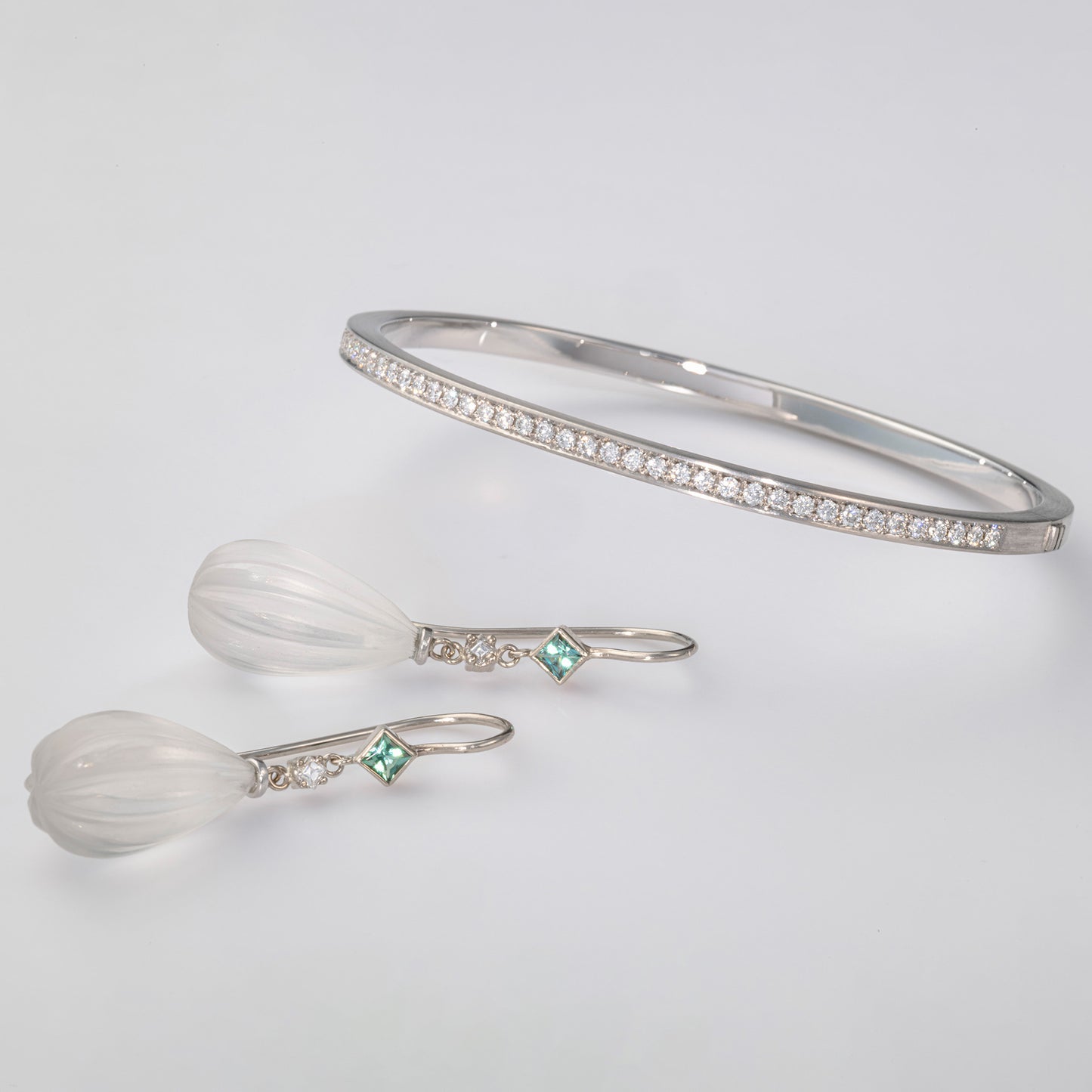 Armreif aus Weißgold mit pavégefassten Diamanten und Ohrringe mit Bergkristall, Brillanten und carrégeschliffenem Turmalin – handgefertigt im Atelier Q.