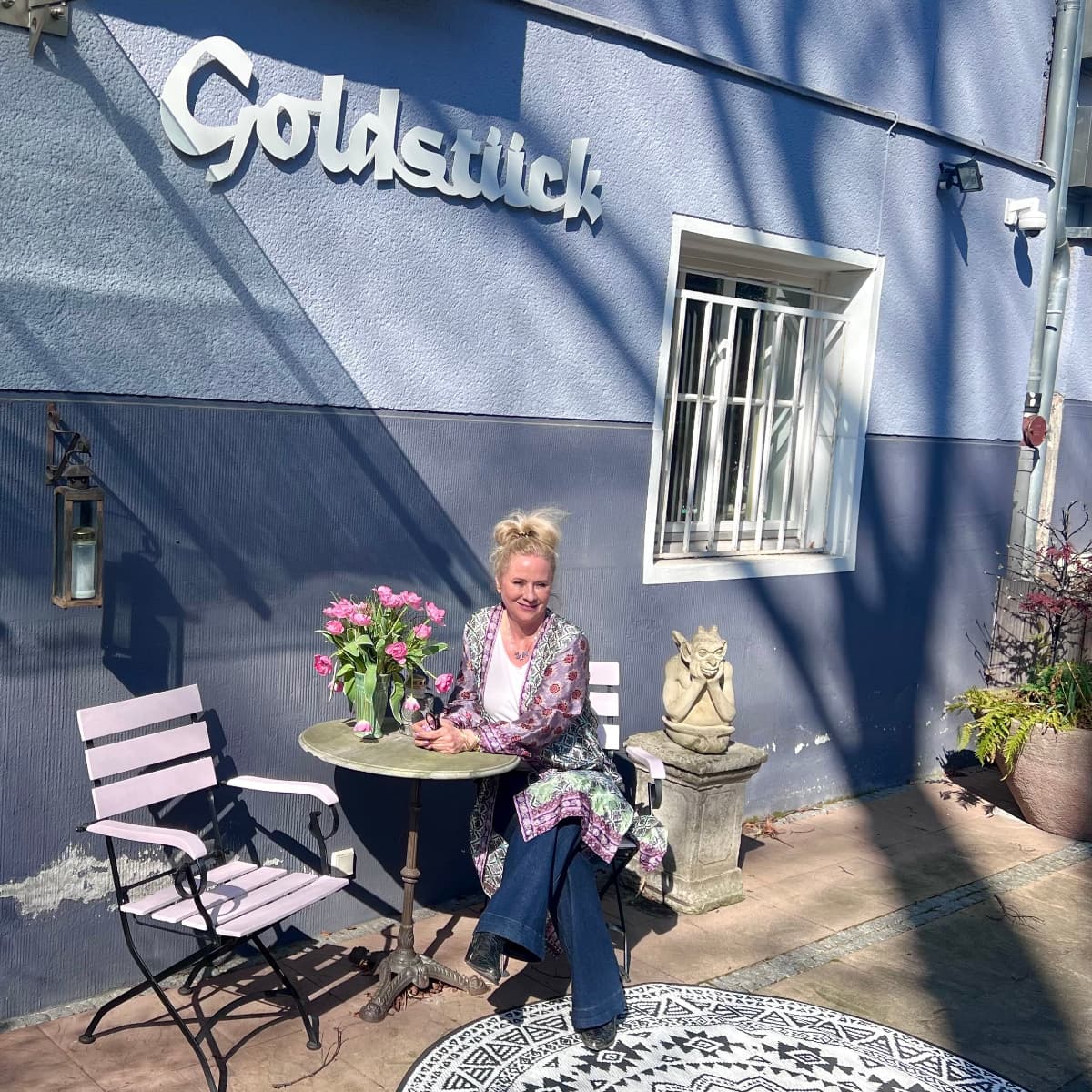 Außenansicht Atelier Q Goldschmiede in Köln mit blauer Fassade, Sitzgelegenheit und Blumendekoration und Andrea Quast 