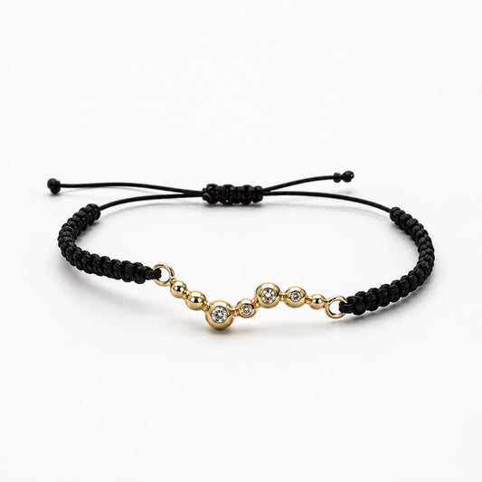 Donut Armband aus 750 Gelbgold mit Brillanten und schwarzem gewachstem Baumwollgarn auf hellem Hintergrund