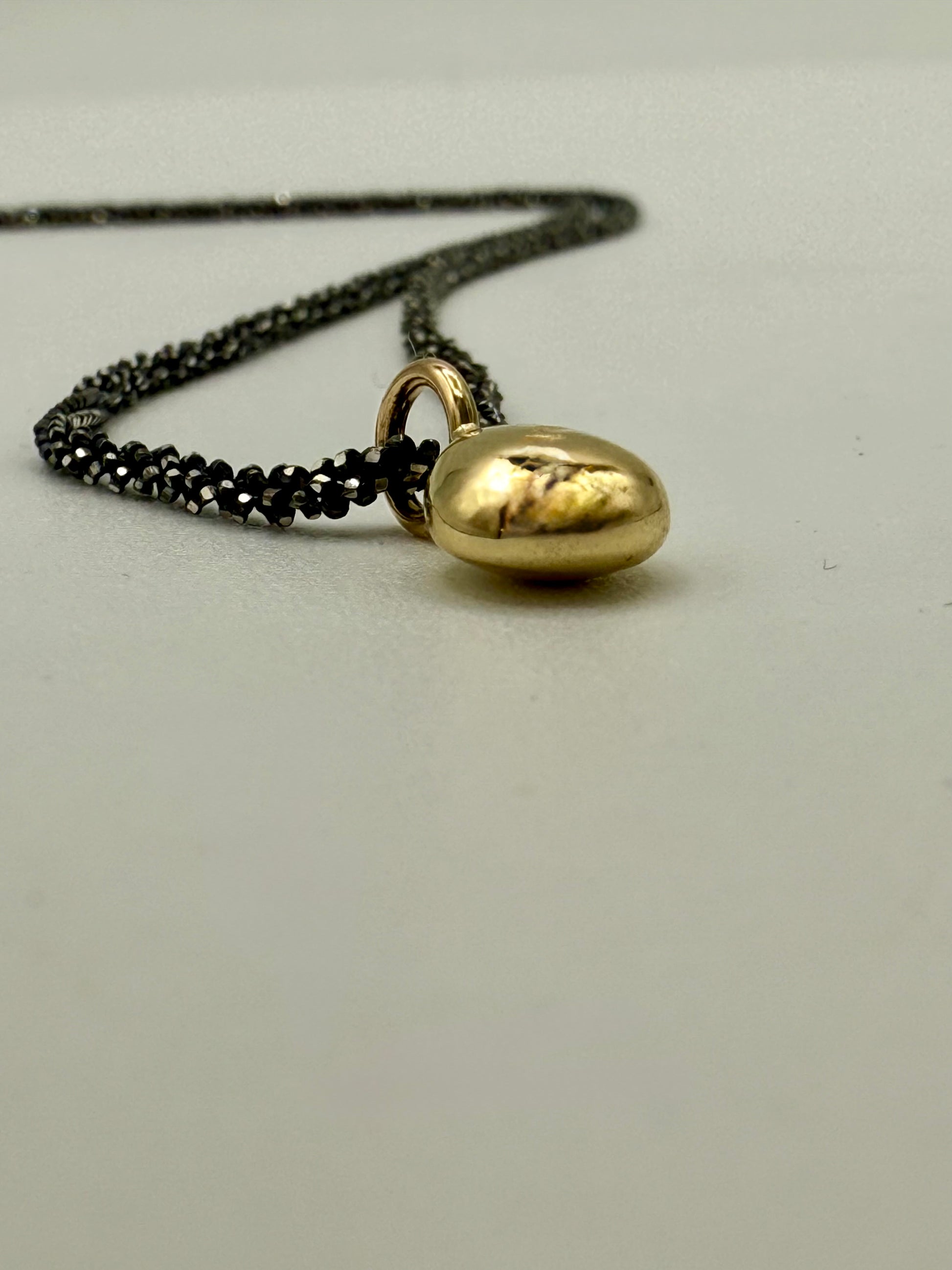 Nahaufnahme von einem Gold Nugget, liegend,mit geschwärzter Silberkette. Unikatschmuck aus Köln. Atelier Q