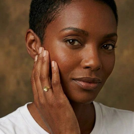 Model mit weißen Tshirt trägt einen goldenen Kleeblattring am Ringfinger