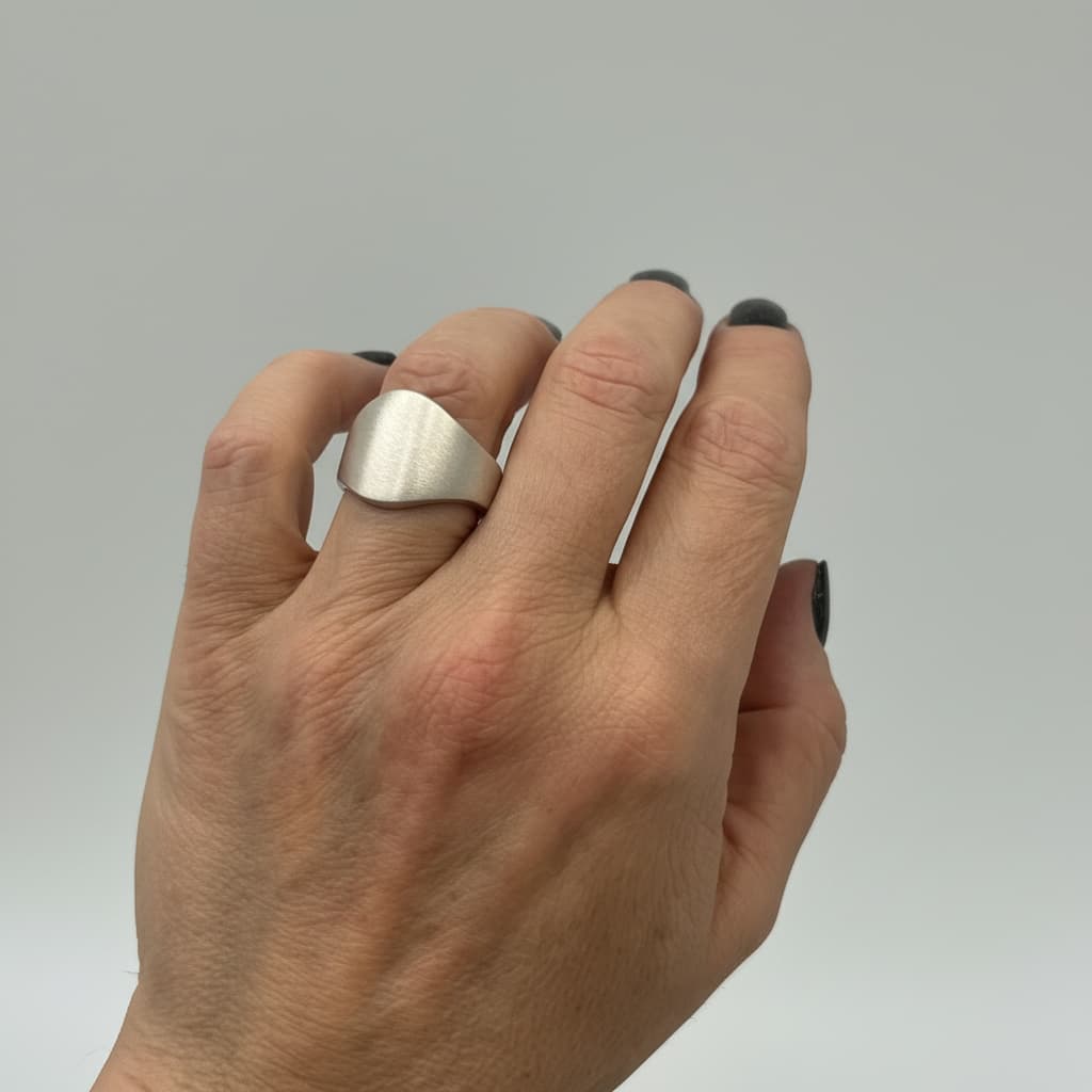 Wappenring Banderole aus recyceltem Silber an einer Hand fotografiert.